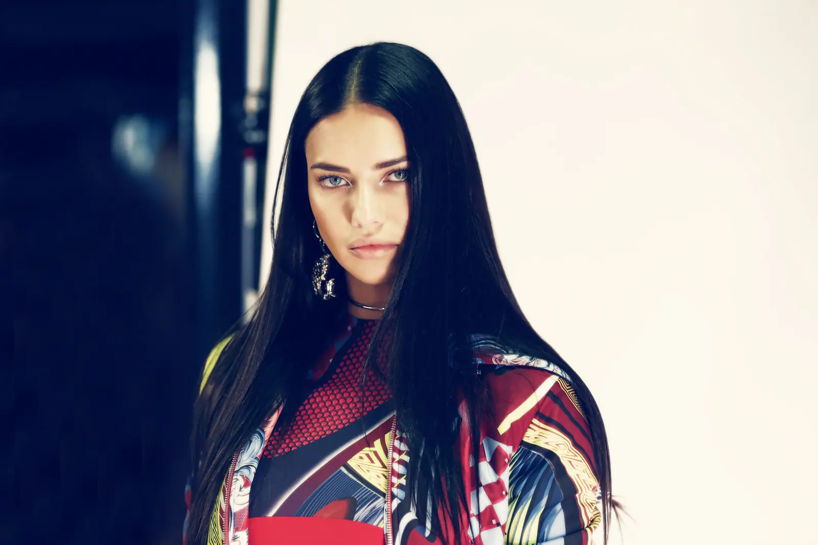 Adriana Lima backstage with long dark hair, in a bold printed top