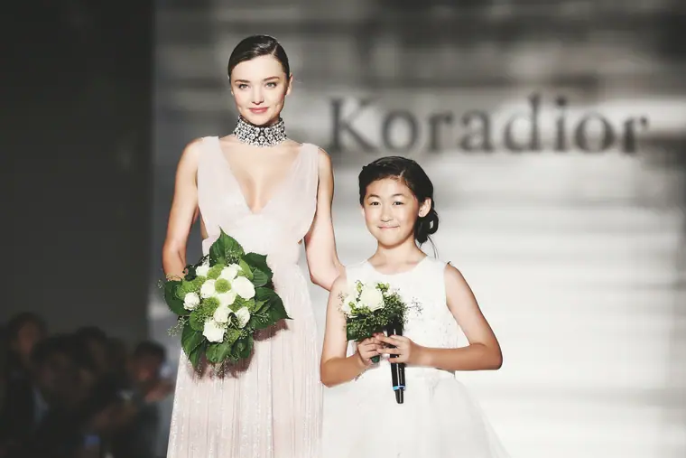Miranda Kerr walking the runway beside a young flower girl