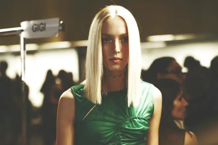 Anique Józsi with platinum hair in a green dress, backstage