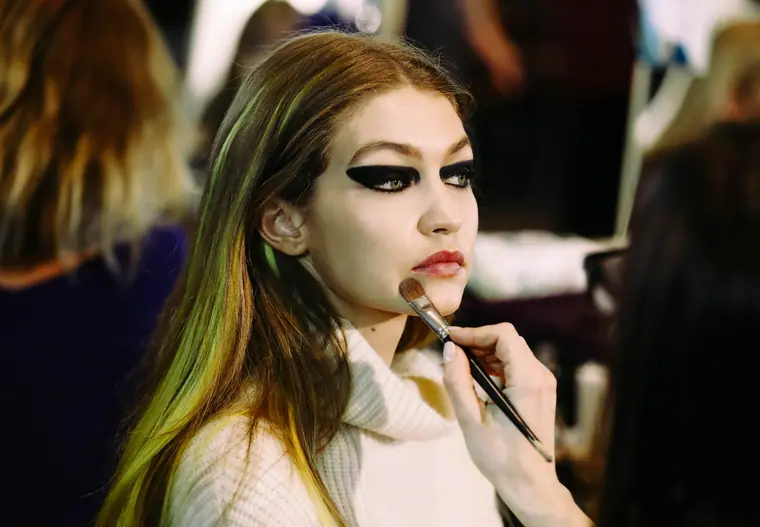 A model receiving dramatic eye make-up backstage