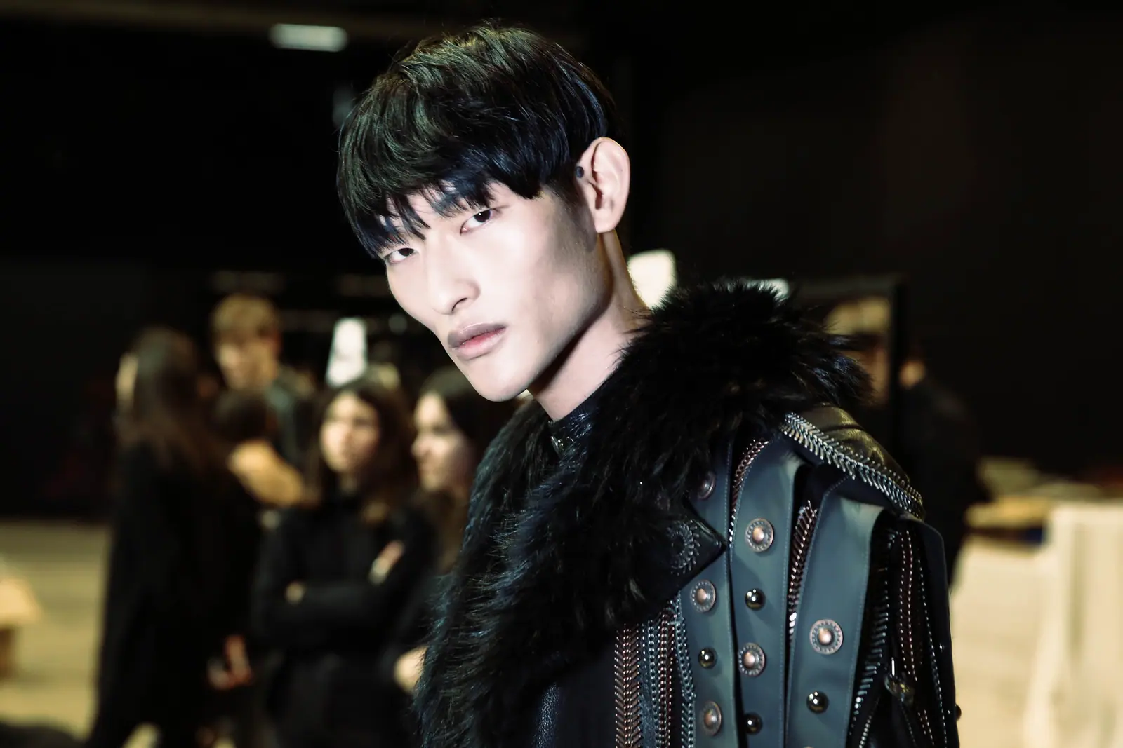 Male model in a fur collar and studded leather jacket, backstage