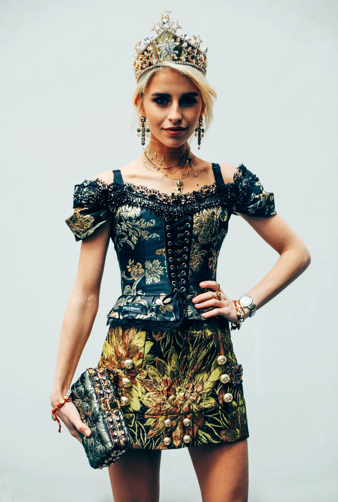 Model in a jewelled crown and brocade dress, hand on hip