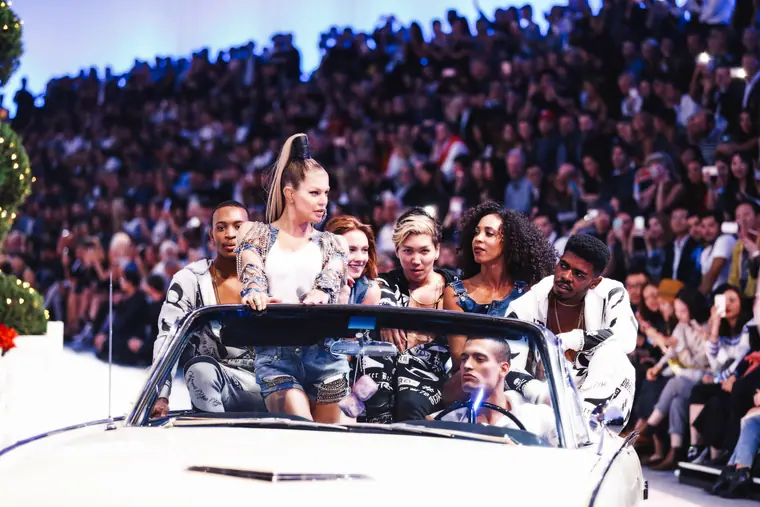 Models riding in a vintage convertible down the runway