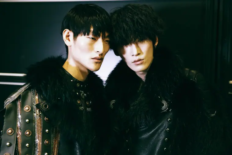 Two male models in fur coats, backstage