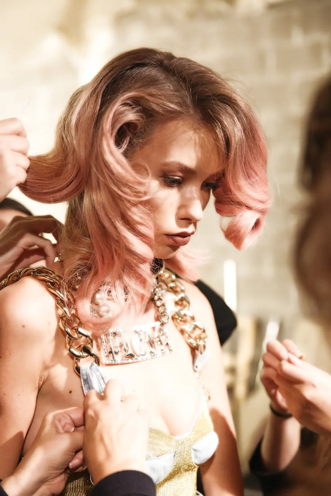 Model with pink-tinted curls during hair styling