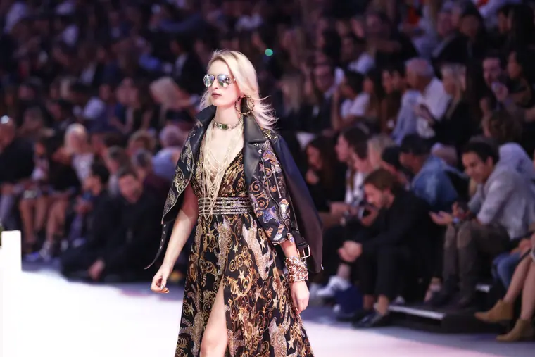Model in a printed dress on the runway, front row behind her