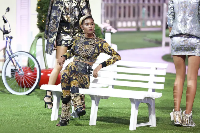 Model on a garden-set runway beside a bicycle and bench