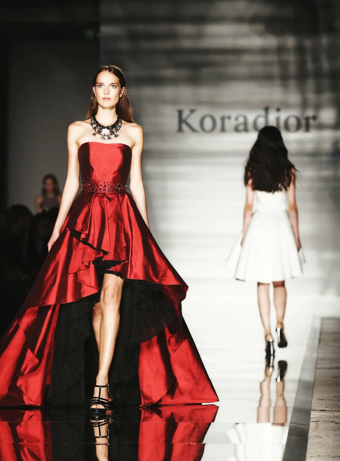 Model in a red high-low gown on the runway