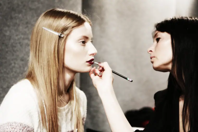Make-up artist applying lipstick to a model