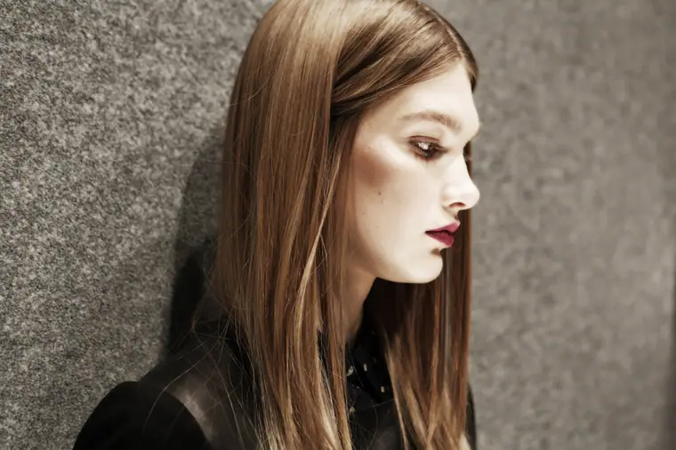 Model with long straight hair in profile against grey