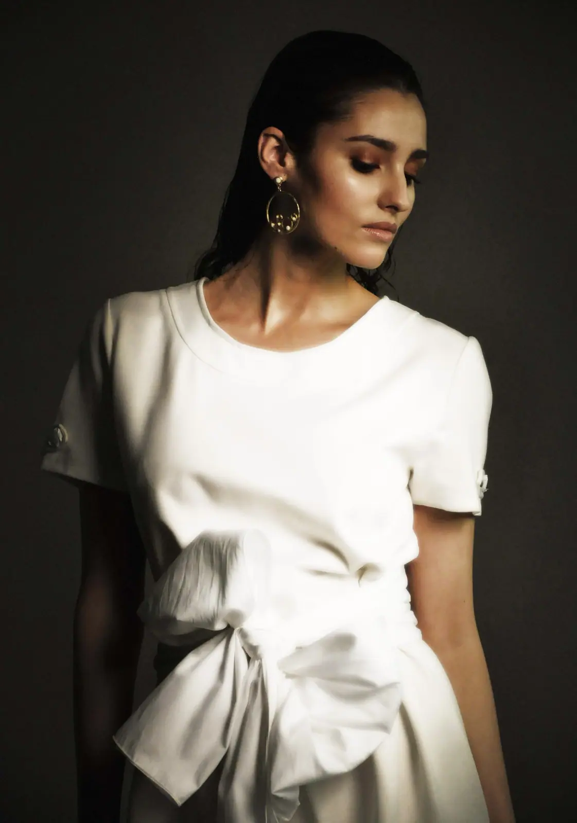 Model in a white tied dress against a dark background