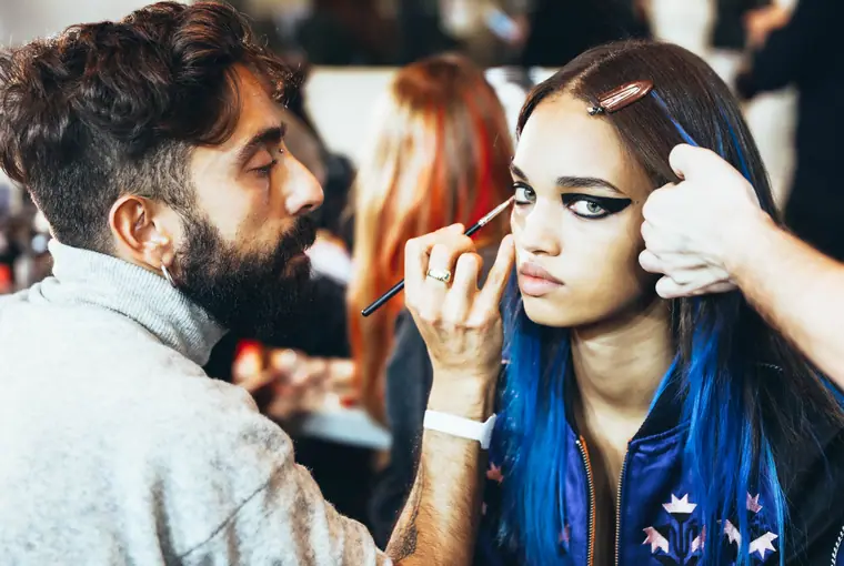Make-up artist working on a model with blue hair