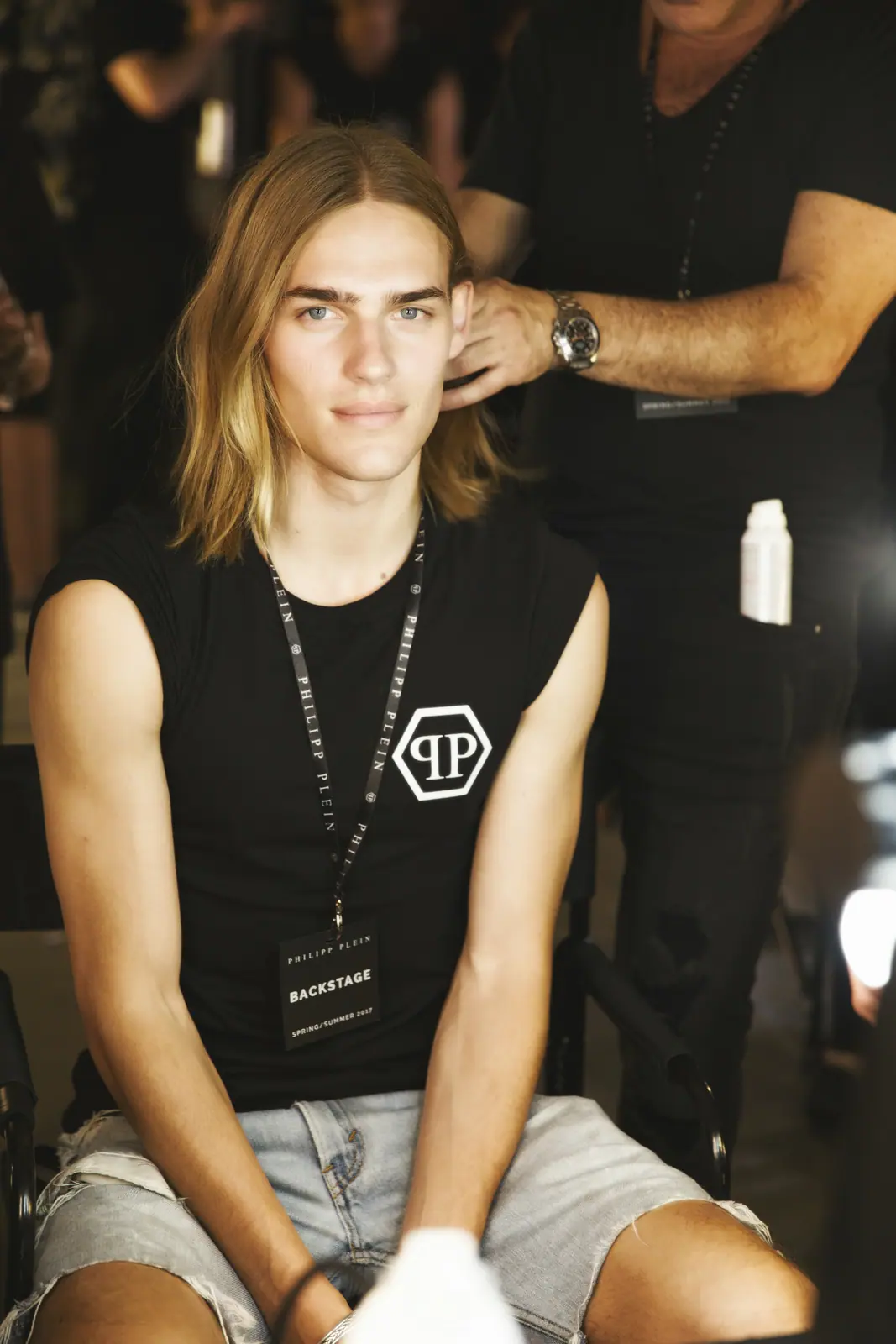 Male model with long hair seated backstage