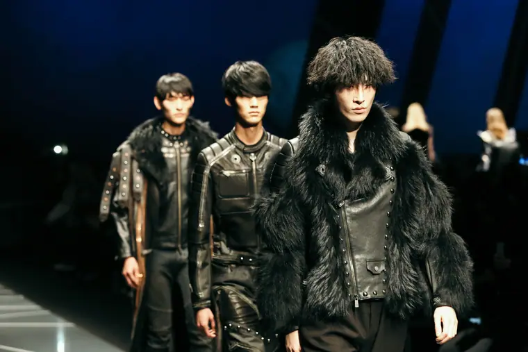 Models in fur and leather on a dark runway