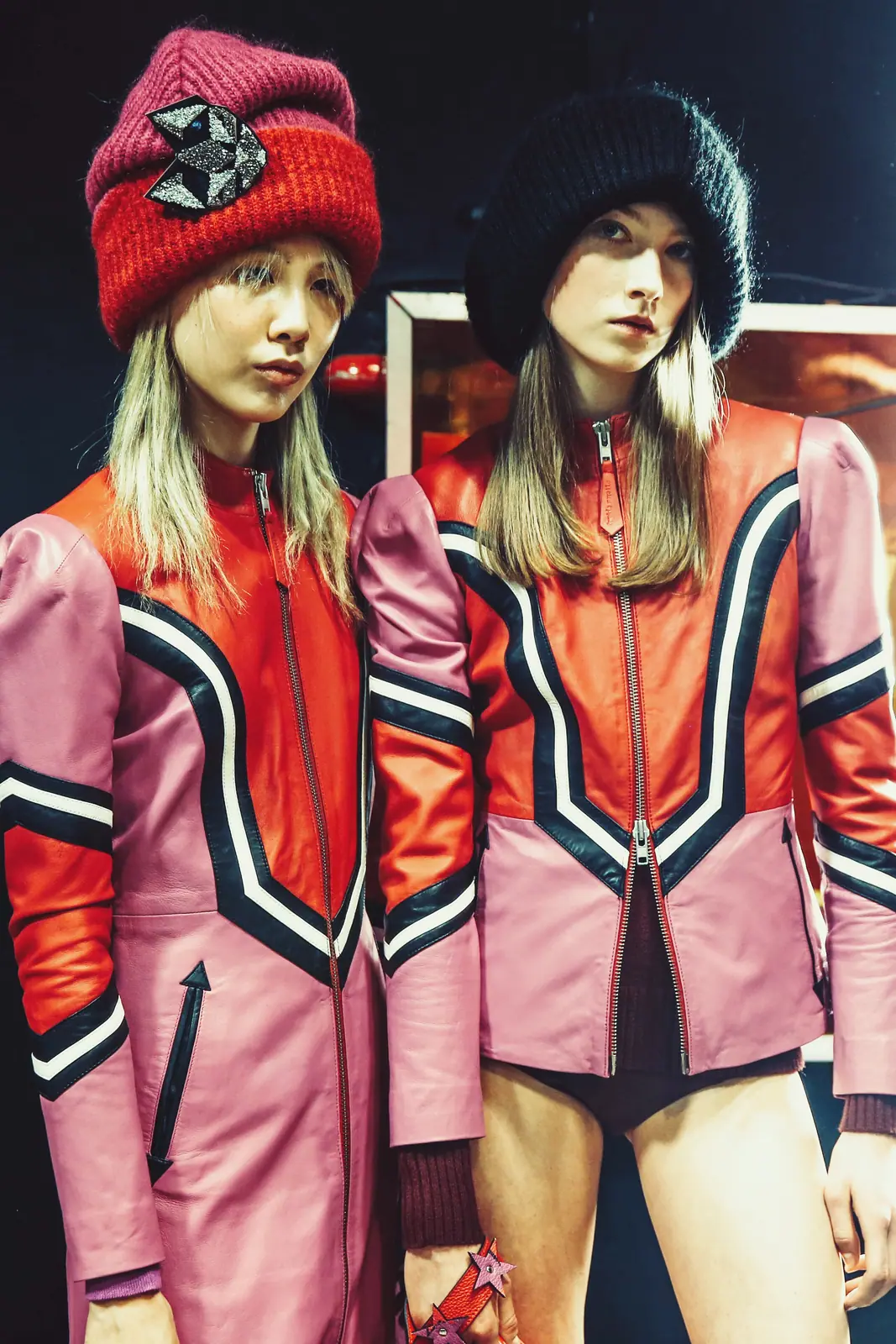 Two models in red beanies and pink sports jackets