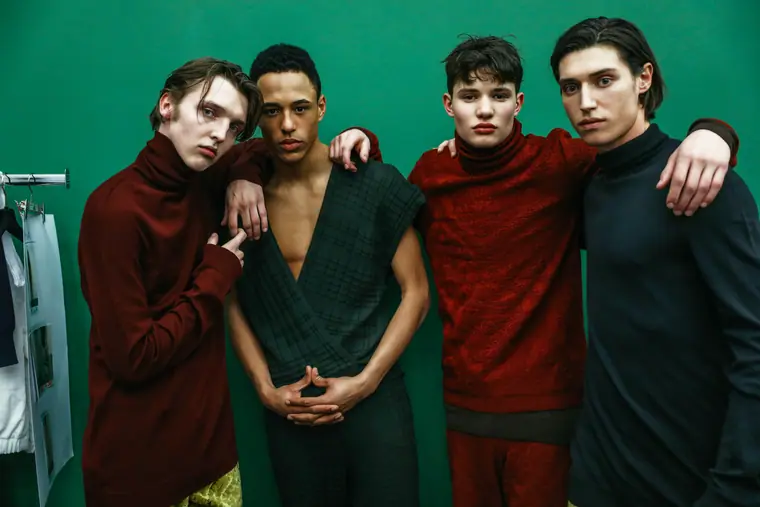Male models in deep red against a green wall
