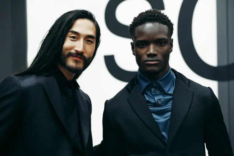 Two models with long hair in dark suits