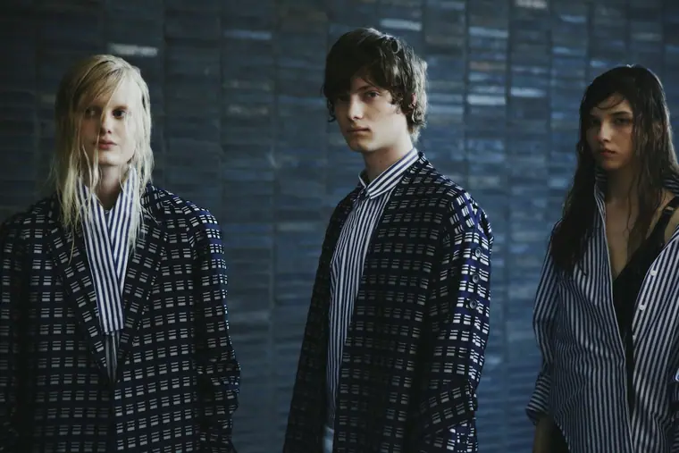 Three models dressed in black, backstage