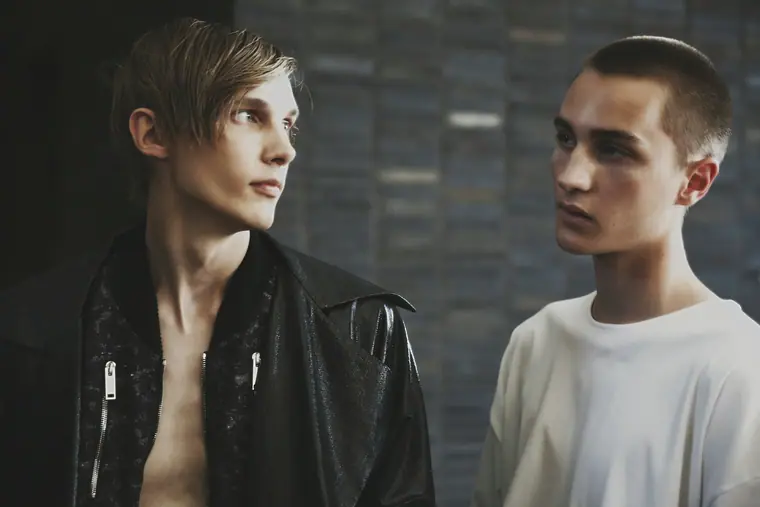 Two male models, one bare-chested under a leather jacket