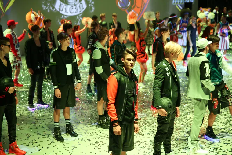 Models in green camouflage on a lawn runway