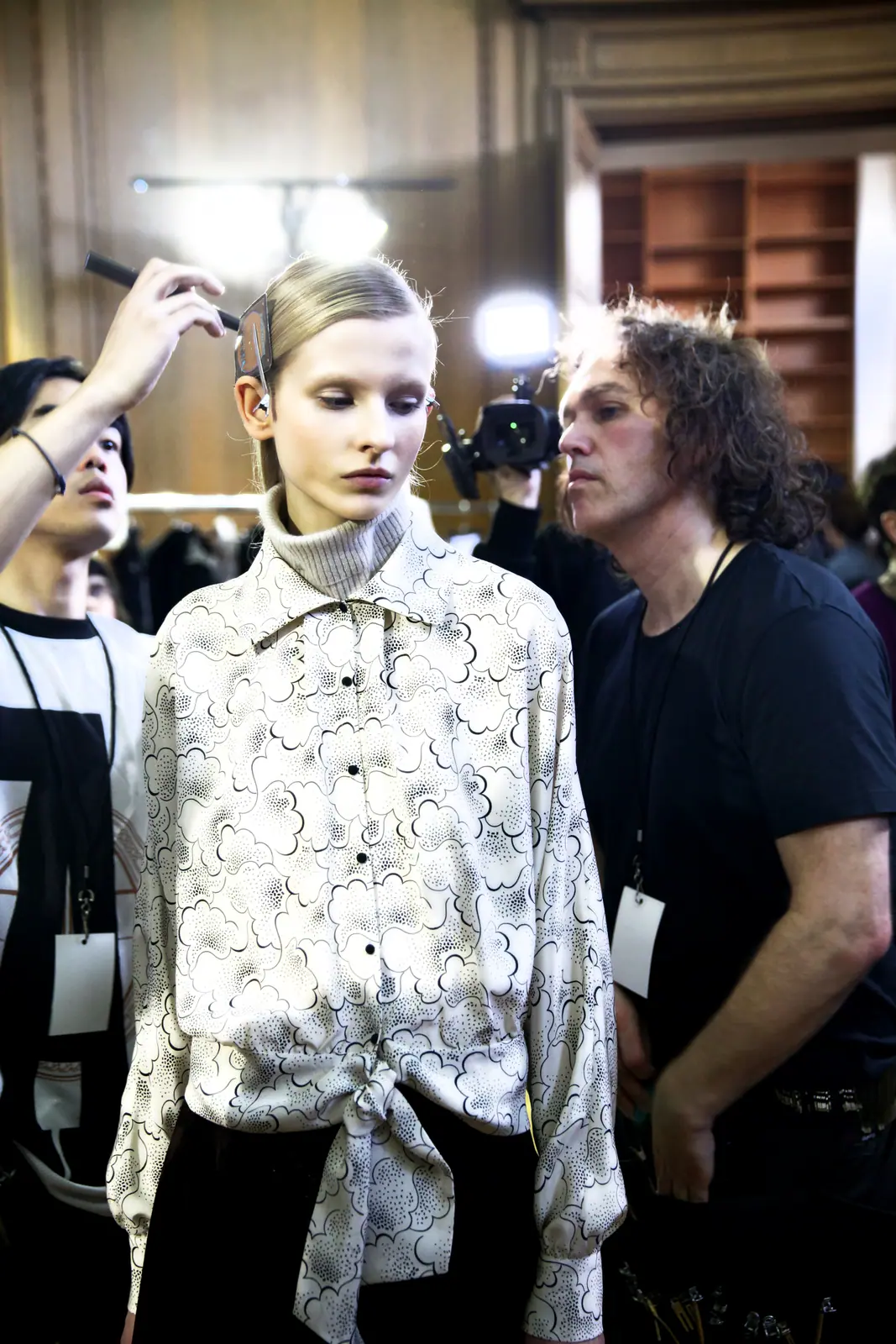Model in a white printed blouse with stylists around her