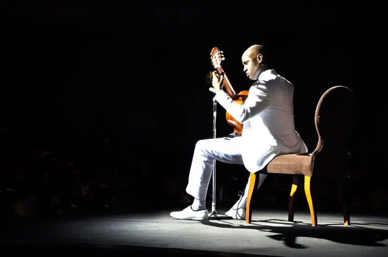 A single model seated in a spotlight on a dark stage