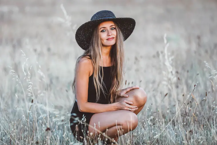Elisha crouching in dry grass in a black hat