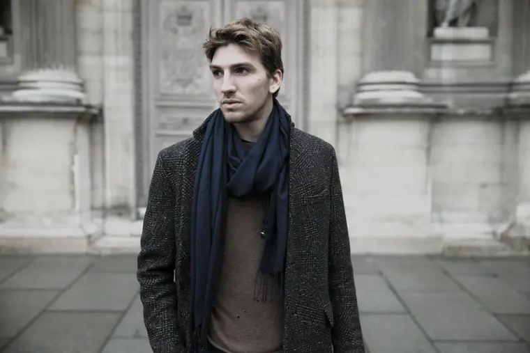 Alan Capelli Goetz in a scarf before stone columns