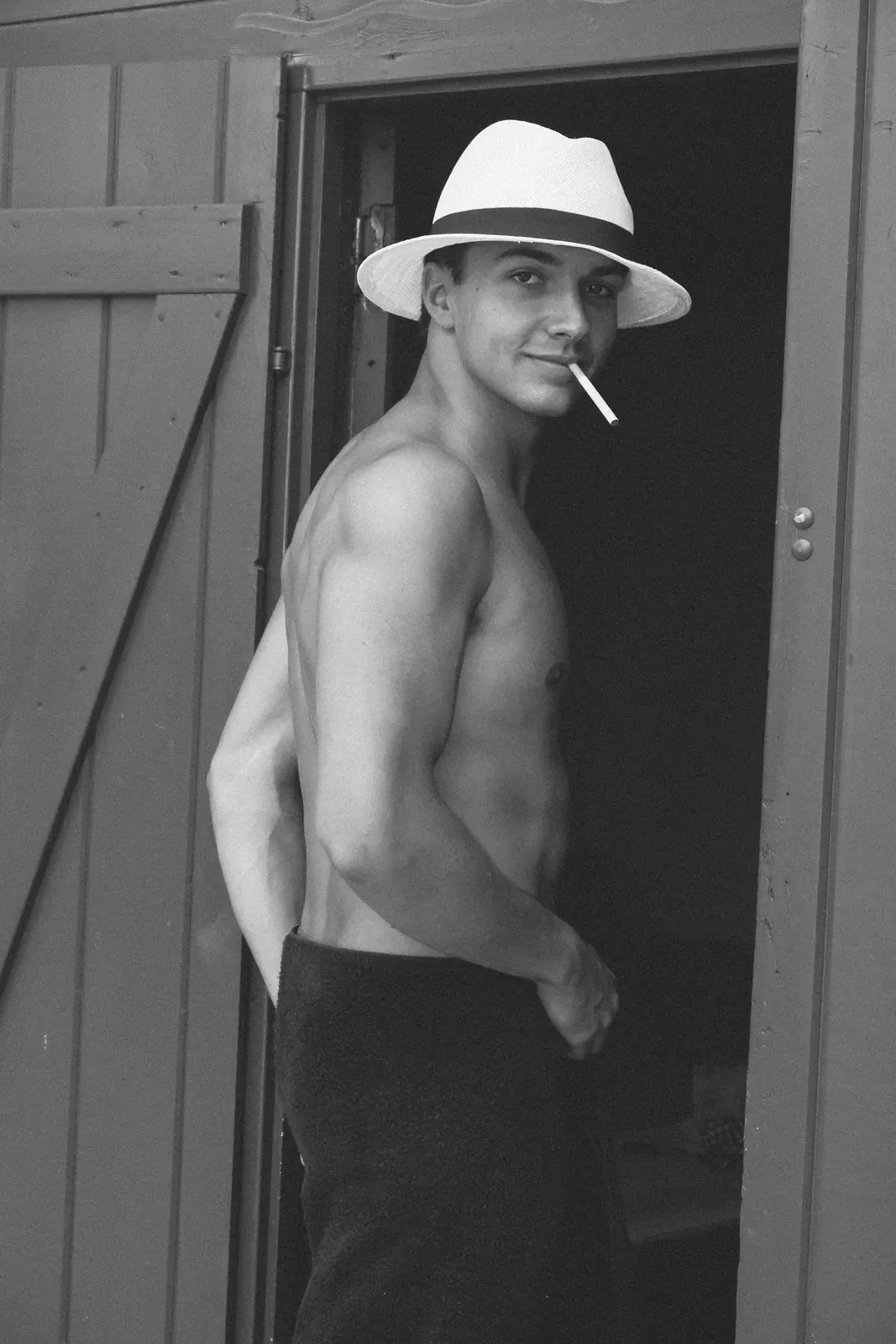 Man in a white hat with a cigarette in a doorway, black and white