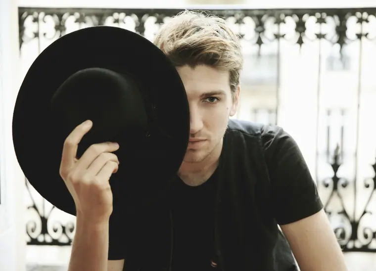 Man holding a black hat in front of his face