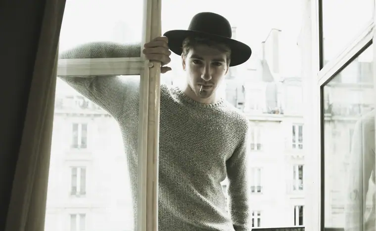Alan Capelli Goetz in a black hat by a window