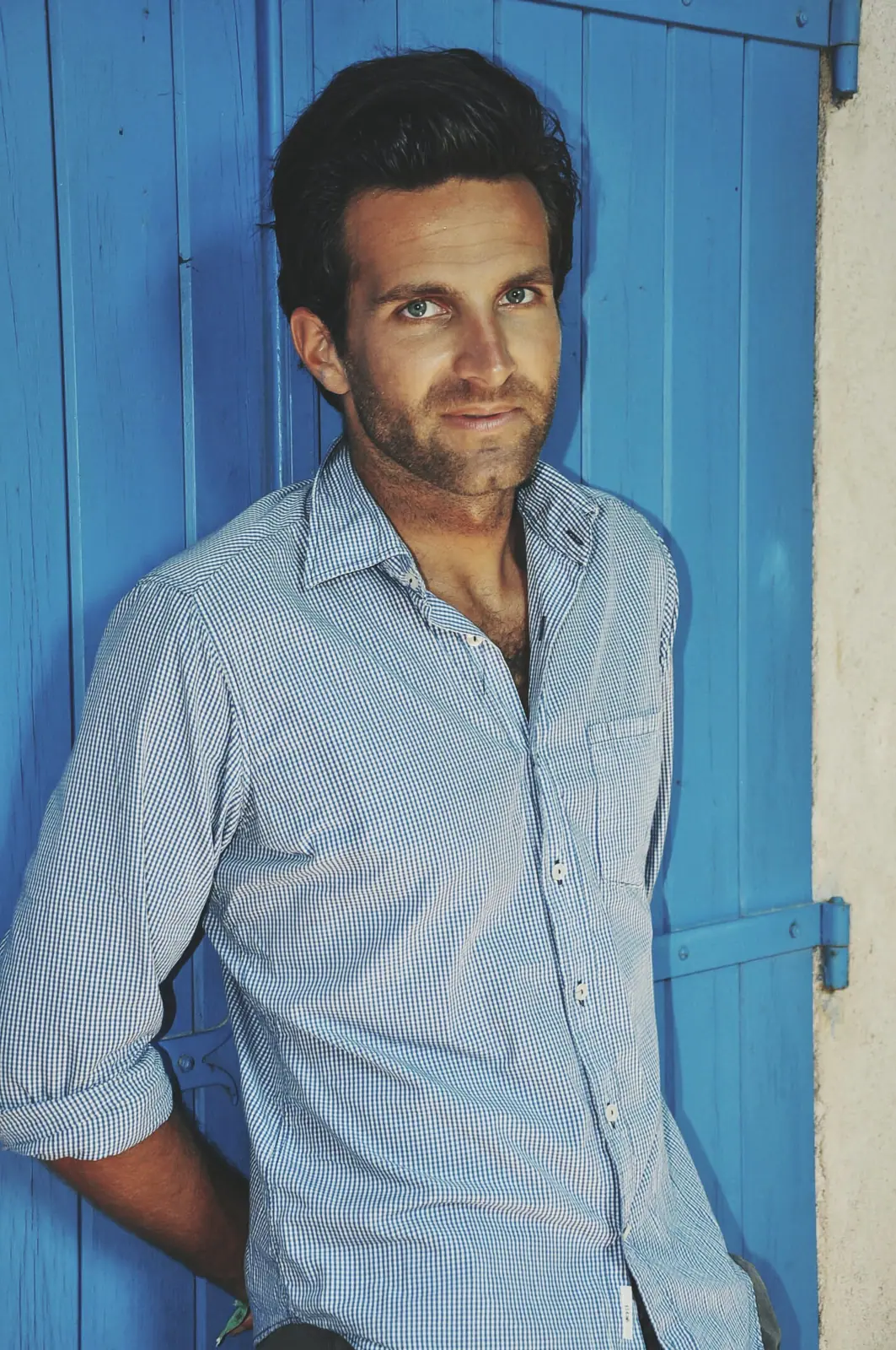 Man in a light shirt leaning on a blue door