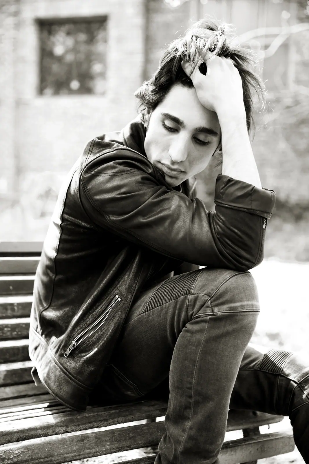 Man in a leather jacket on a bench, black and white