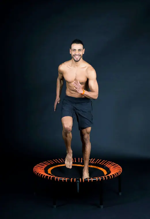 Man on a mini trampoline against a dark backdrop