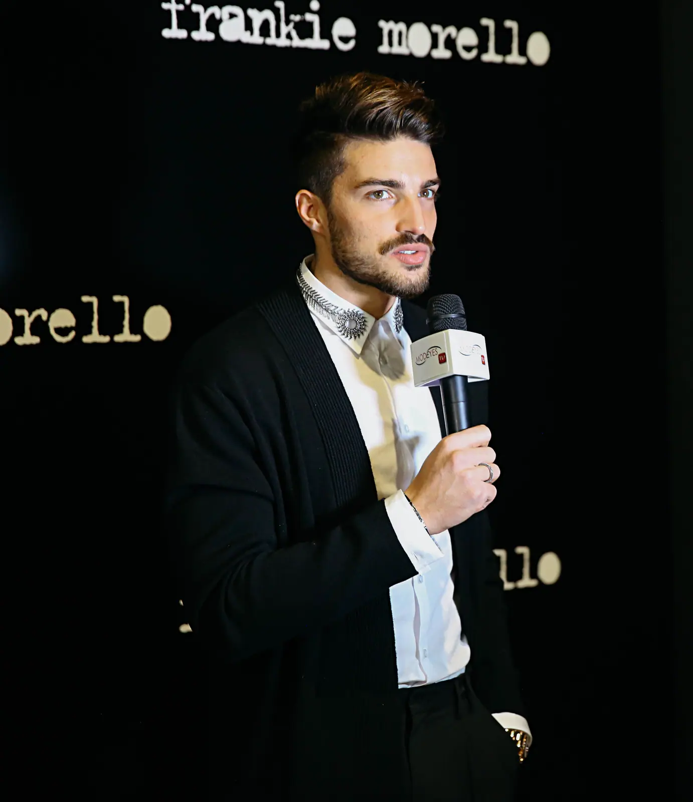 Man with a microphone at a press wall
