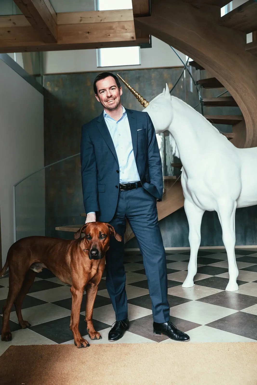 Tobias Reichmuth with his dog beside a white unicorn sculpture